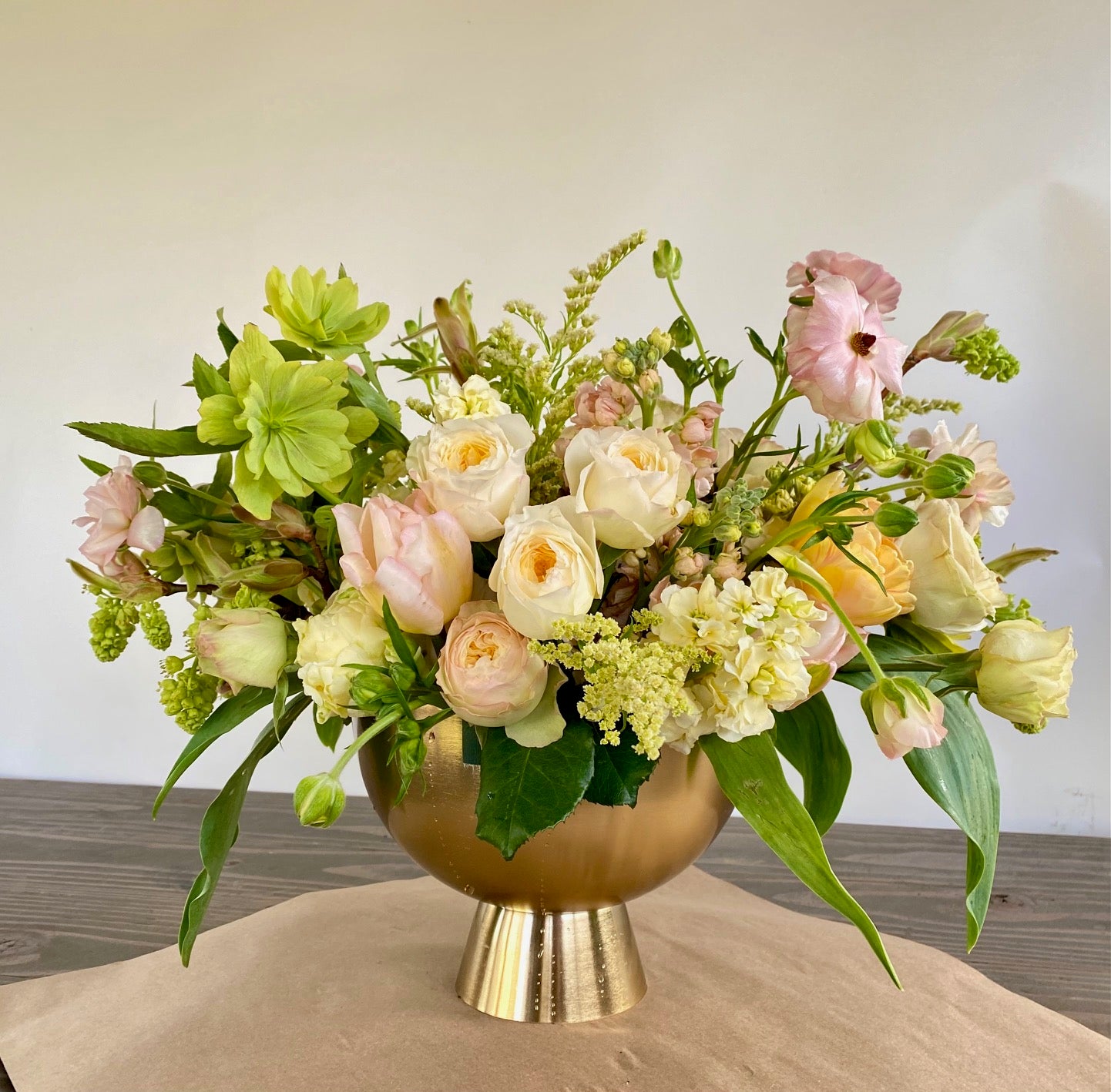 Pastel flower arrangement in brushed gold compote with roses, tulips and hellebore